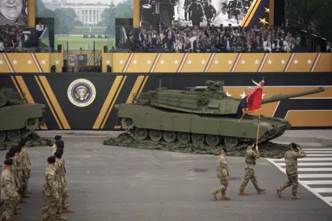 Getty Images US soldiers march past Donald Trump as a tank rolls past - the president stands and salutes them from the stands.