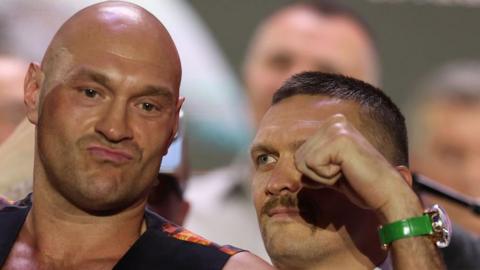 Tyson Fury looks ahead as Oleksandr Usyk stares at him during a face-off