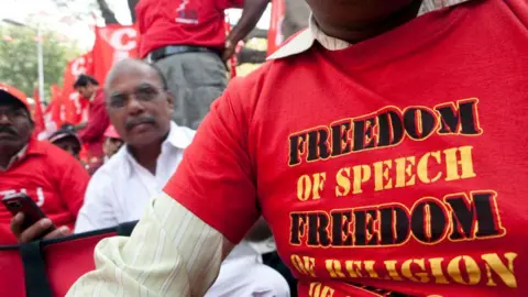 Getty Images Seorang pekerja serikat pekerja mengenakan kaos untuk kebebasan berbicara, agama dan pilihan, selama pawai protes ke Parlemen Street, di New Delhi, India, pada hari Rabu, 23 Februari 2011. Ribuan pekerja dari seluruh India rally Oleh serikat pekerja memulai pawai menuju parlemen negara di New Delhi Tengah hari ini memprotes kenaikan harga pangan, upah rendah dan keamanan kerja. Fotografer: Prashanth Vishwanathan/Bloomberg via Getty Images