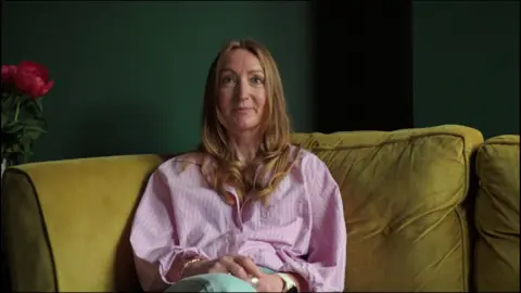 A woman with long blonde hair and a pink shirt sat on a yellow sofa