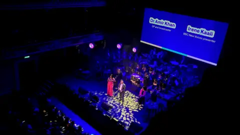 BBC BBC New Voices presenter Irene Kaali and Dr Amir Khan on stage in St George's Hall