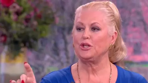 A lady with blonde hair wearing a blue top