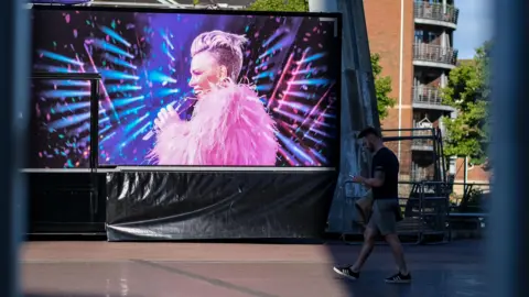 A billboard of Pink in Cardiff with a person walking by