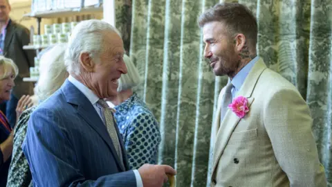 PA King Charles smiles as he meets David Beckham