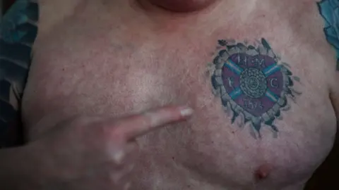 Reuters A Hearts fan points to a tattoo of the club's claret crest on his chest.