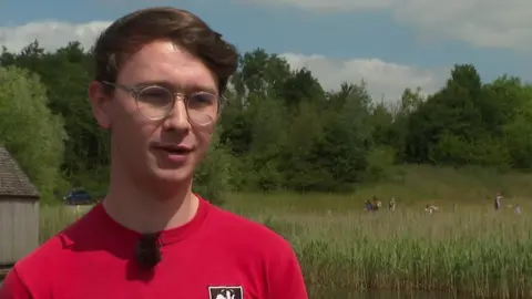 Philip Gwynn in red T-shirt wearing glasses