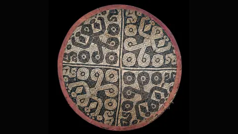 Pitt Rivers Museum A round hat with a red-ish outline. The middle consists of a black and white pattern made from bamboo.