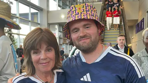 A woman and man wearing Scotland strips
