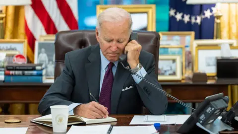 President Joe Biden talks on the phone in the Oval Office
