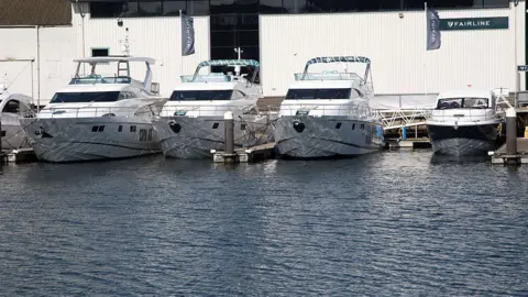 Four white small yachts docked in the bay on water. 