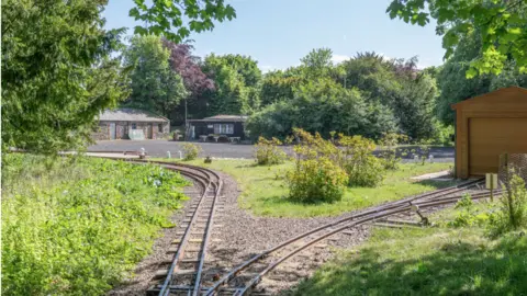 Knight Frank Narrow train tracks across a garden