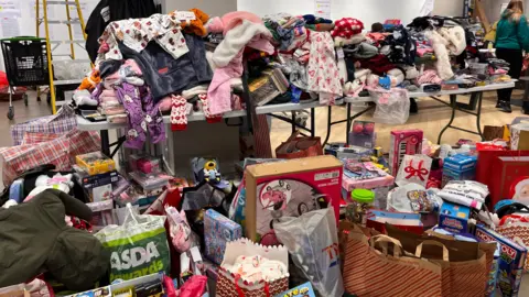A table overflows with cloths, toys and games