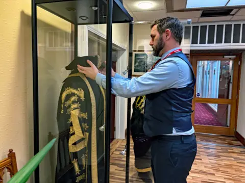 Ian Duncan Lee Paton puts the old mayoral robe on display in a glass cabinet.