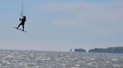 south_coast_sanctuary A kitesurfer high above the sea, with the cliffs of the Dorset coast in the background.