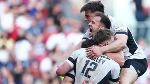 Tobias Elliott yells in delight as he hugs his team-mates in celebration of scoring a late try to seal their win over Bristol.