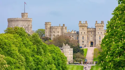 A general view picture of Windsor Castle, with the entrance gates and people stood outside them at the bottom of the picture.
