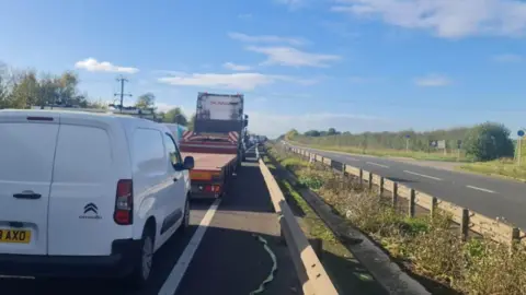 Katharine Coulston/BBC A long queue of traffic on one side of the A12. The opposite path is empty.