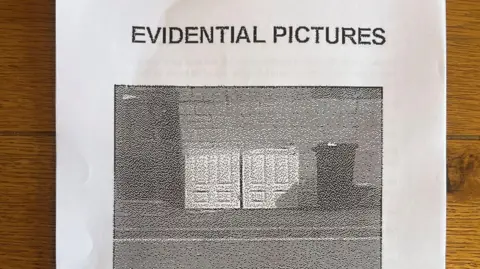 A piece of A4 paper with an image of the doors cut in half and resting against a wall next to a bin. There is writing which says evidential pictures above the image.