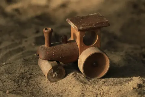 Doris Enders A wooden toy train on sand