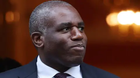 EPA David Lammy, dressed in a suit and tie, looks off to the right.