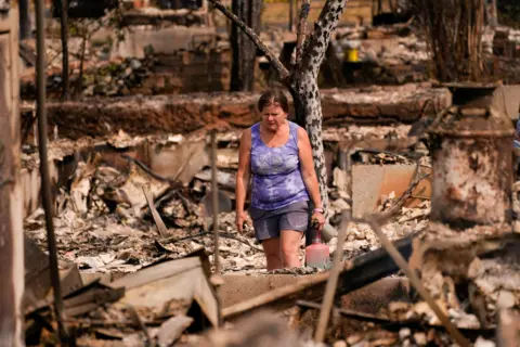 Reuters A woman in Spokane, Washington, surveys the damage of her burned down home