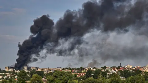 EPA Black smoke billows out over the Kharkiv skyline from a large building that appears bombed out.