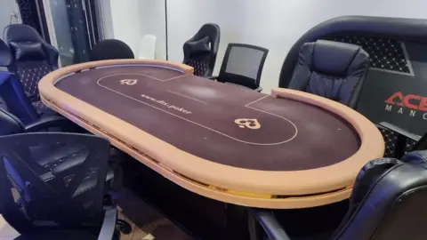 GMP A maroon poker table next to black chairs