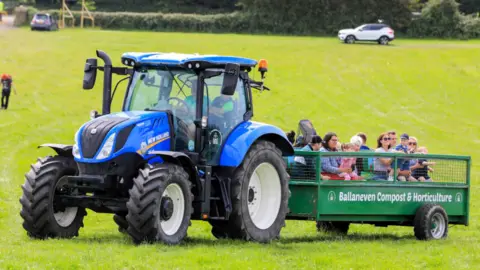 CJS Photography A tractor pulls a trailer of families holding young children