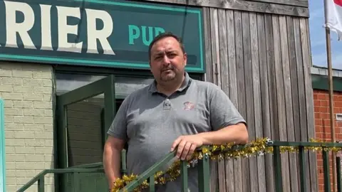 A view of a man stood in front of a pub.