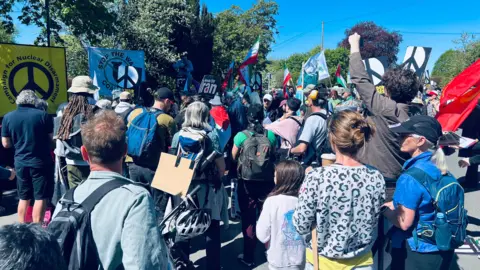 People have gathered on a street in a protest, holding flags and placards.