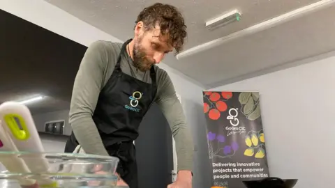 Cookery course teacher Rob Hewis is slicing an onion