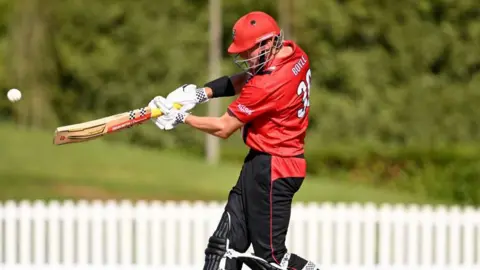 Matt Boyle batting for Canterbury Kings, wearing red shirt and dark trousers