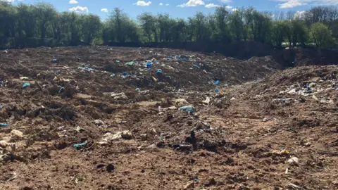 Environment Agency/Natural England A vast swathe of soil and rubbish leading to a line of trees
