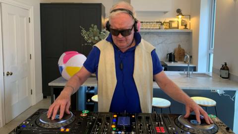 Julian Simmons playing with decks waring sunglasses and pink sparkly headphones 