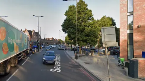 Google A Google Maps screen grab of the Seven Sisters Road with cars and lorries on the road and green trees on the pavement. 