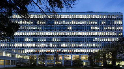 Getty Images Velká univerzitní budova v noci. V některých oknech svítí světla.