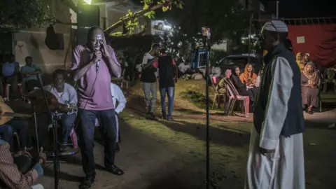 Pictures of Bloomberg / Getty Mashta Night showing a man in T -T -shirt singing in a microphone with musicians behind him and others who look at him.