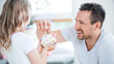 Getty Images Parent gives child pocket money
