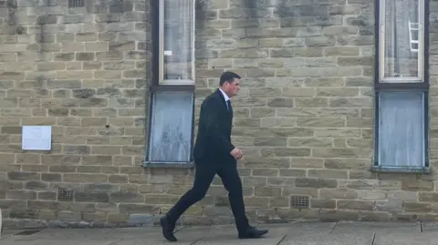 Steve Jones/BBC Racster Dingwall, pictured arriving at court in a black suit. He has black hair and is of average build.
