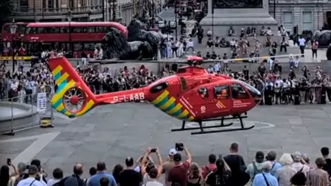 Air ambulance lands in a crowded Trafalgar Square.