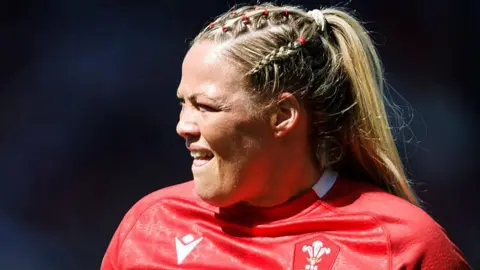 Kelsey Jones playing for Wales on a very sunny day as she squints looking towards the sunlight 