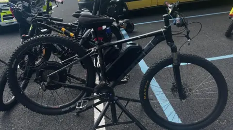 Merseyside Police A black and grey mountain bike with a battery pack visible on the frame, above the pedals and between the two wheels.