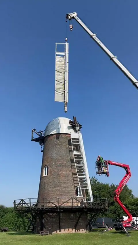 Windmill with sale being taken off by crane.