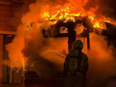 Josefina Sesti Lagoa A firefighter silhouetted as they tackle a bus engulfed in flames