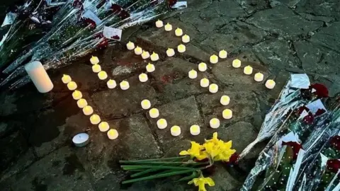 Candles and flowers left on the pavement outside the premises of Legacy Independent Funeral Directors, in Hessle Road, Hull. The candles have been lit and spell out "35" which relates to the number of bodies recovered by police.