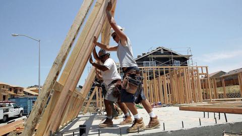 Construction workers raise wood framing as they build homes in a new housing development  in Richmond, California.