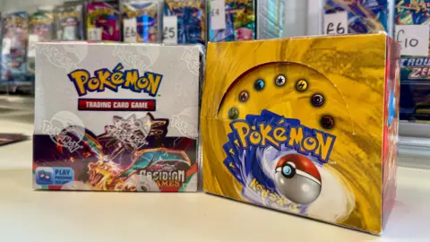 Danny Fullbrook/BBC Two Booster Pokemon Card Booster Boxes duduk bersebelahan. Yang satu lebih tua, dari tahun 90 -an, yang lain adalah edisi terbaru.