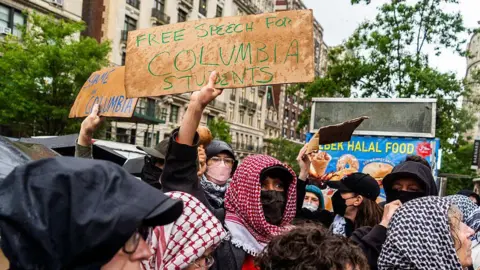 Protesters wearing Arabic scarfs at Columbia. One holds a sign calling for free speech for Columbia students