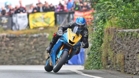 MANX GRAND PRIX Ingham racing in the MGP while crowds look on behind.