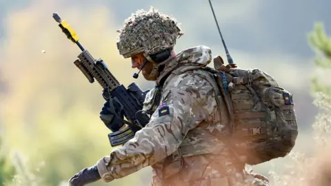 Profile view of a British Army soldier training in battle dress and a rifle